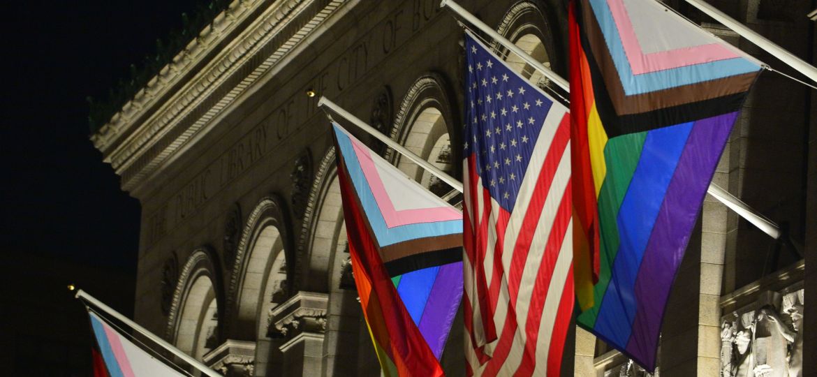 The Unity Flags along with the American flad hang on the outside on the Boston Public library during the evening.