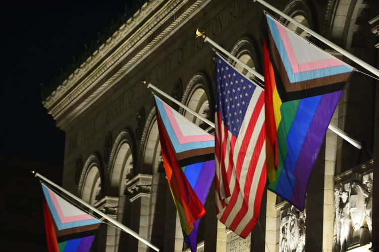 The Unity Flags along with the American flad hang on the outside on the Boston Public library during the evening.